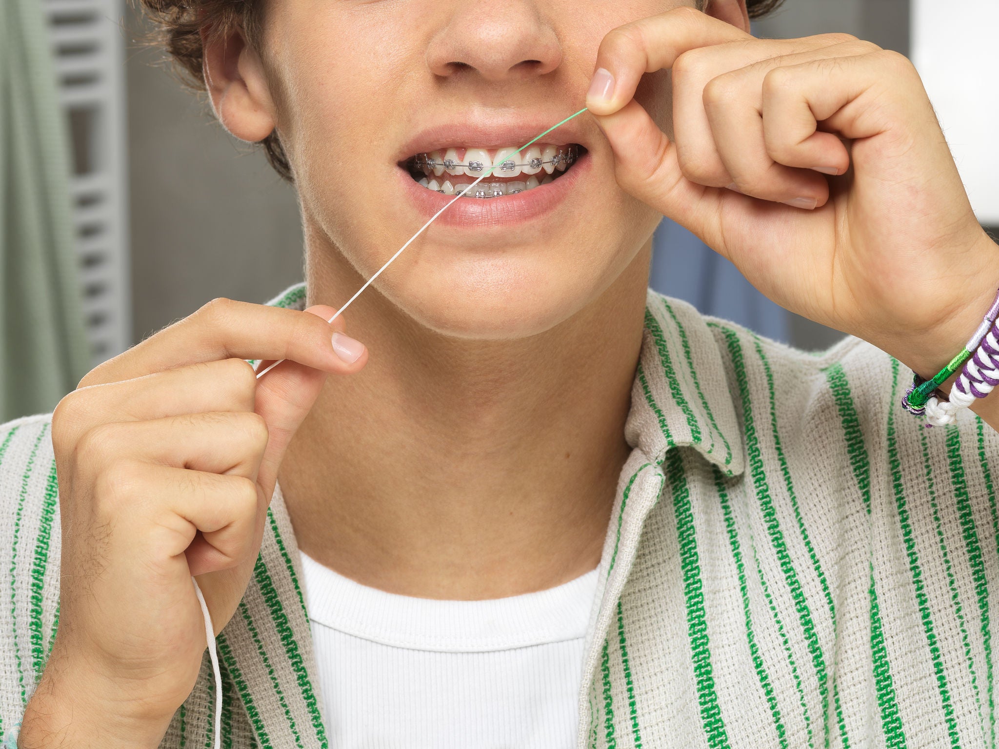 Teen is flossing with GUM ORHO floss