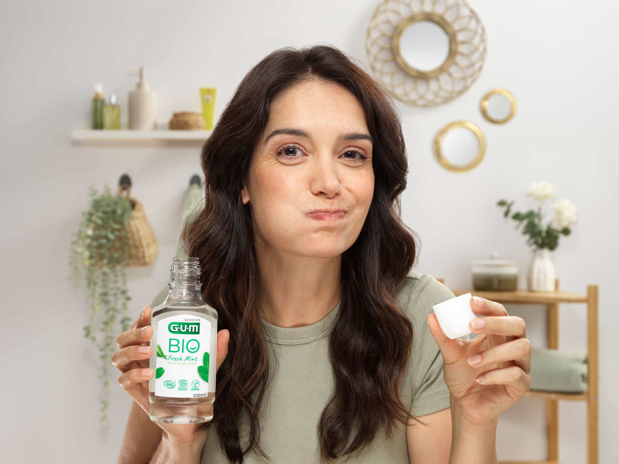 Woman is rinsing her mouth with the GUM BIO Mouthwash in a natural and green environment