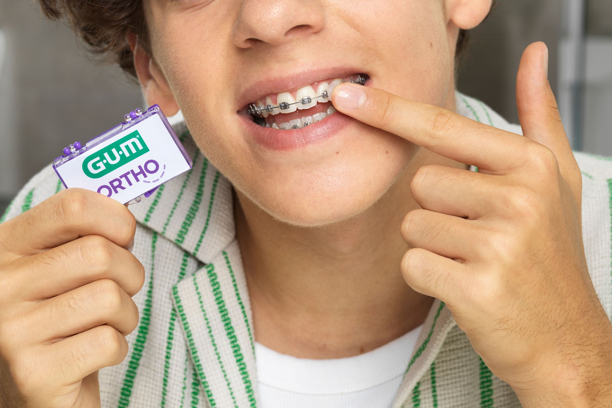 A teenager with braces holds a GUM ORTHO product, demonstrating oral care. The focus is on maintaining dental hygiene with braces.