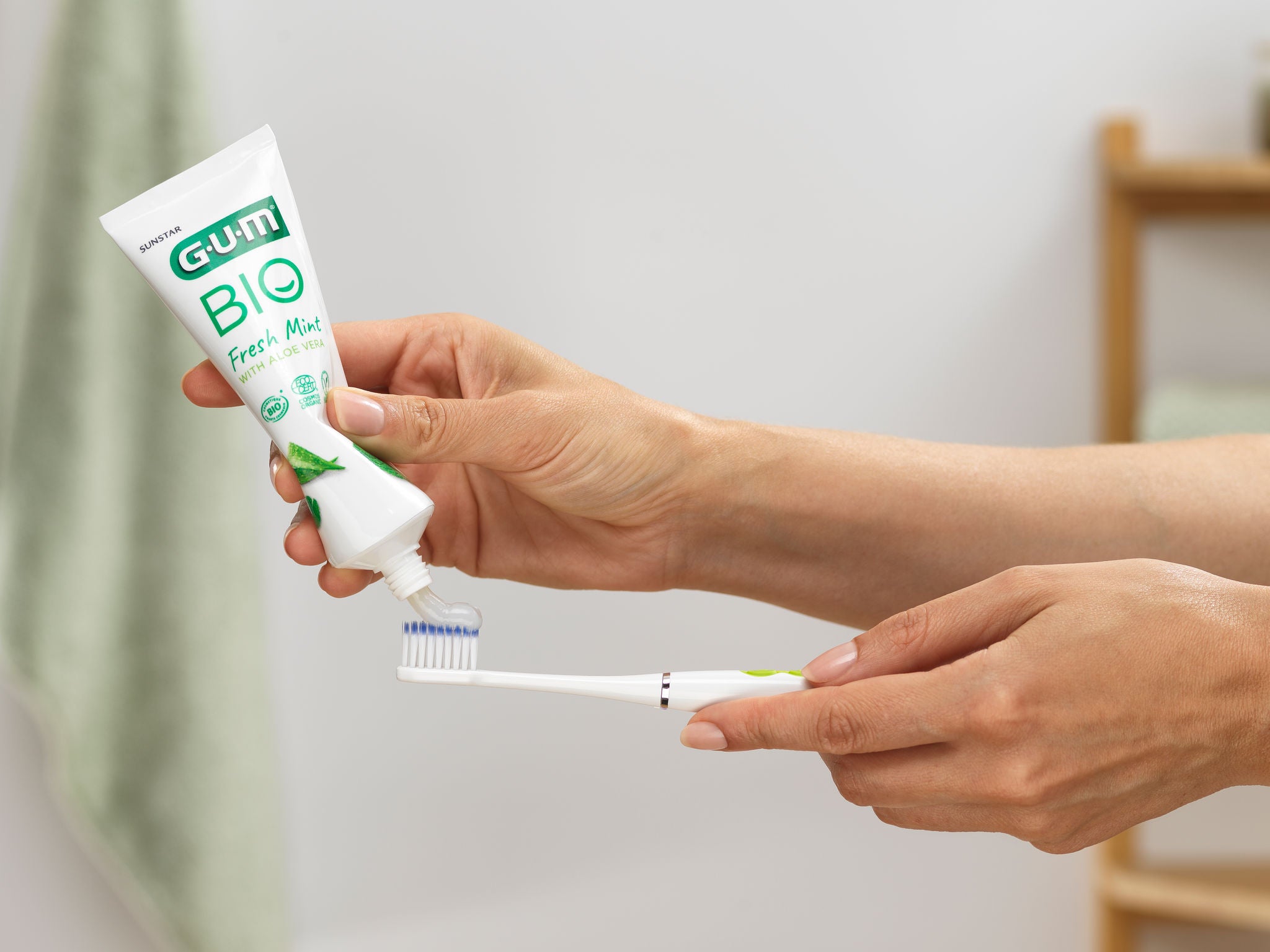 Woman is pressing the GUM BIO toothpaste to put it on her GUM SONIC DAILY toothbrush