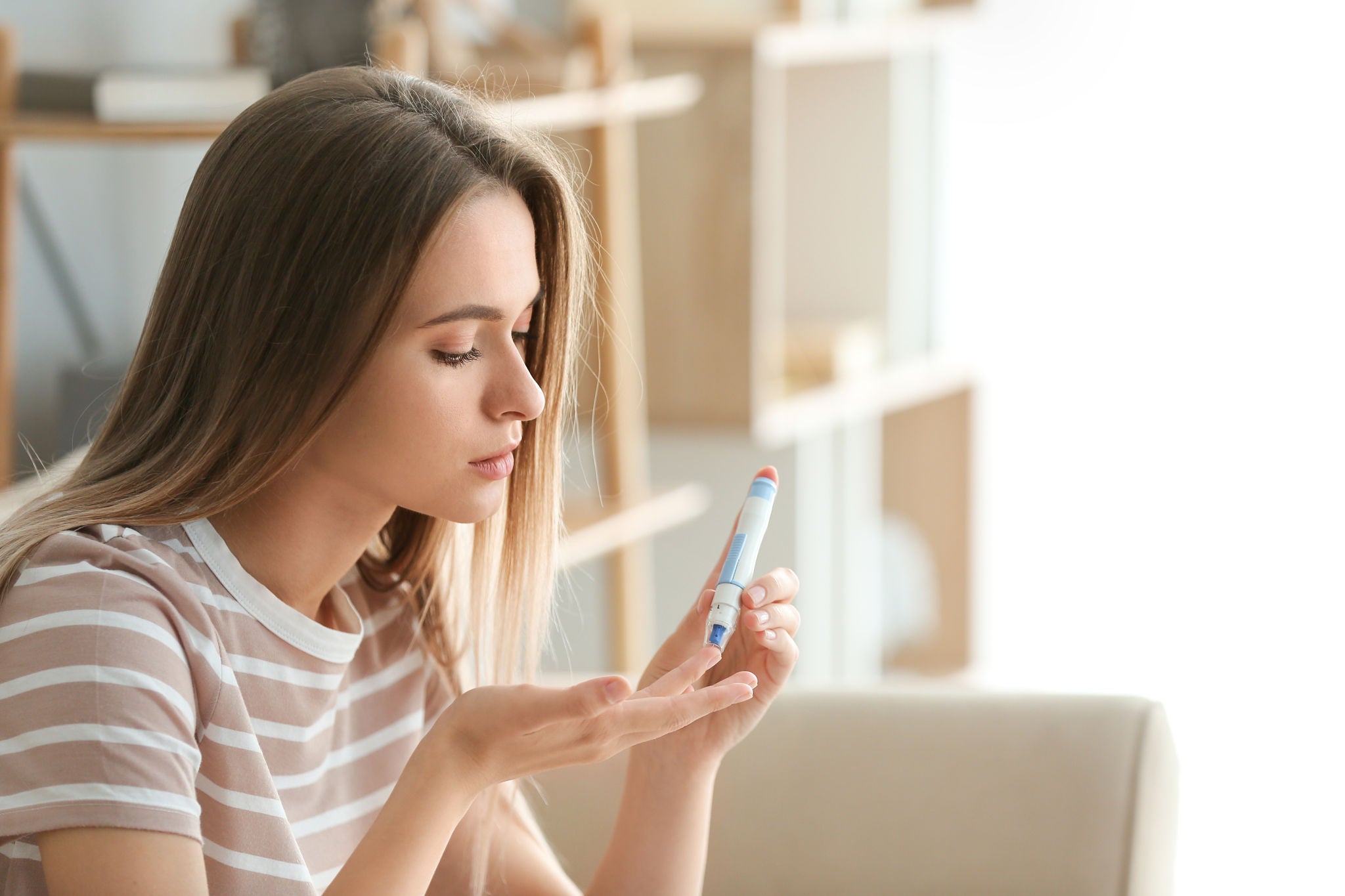 Diabetic woman checking blood sugar level at home