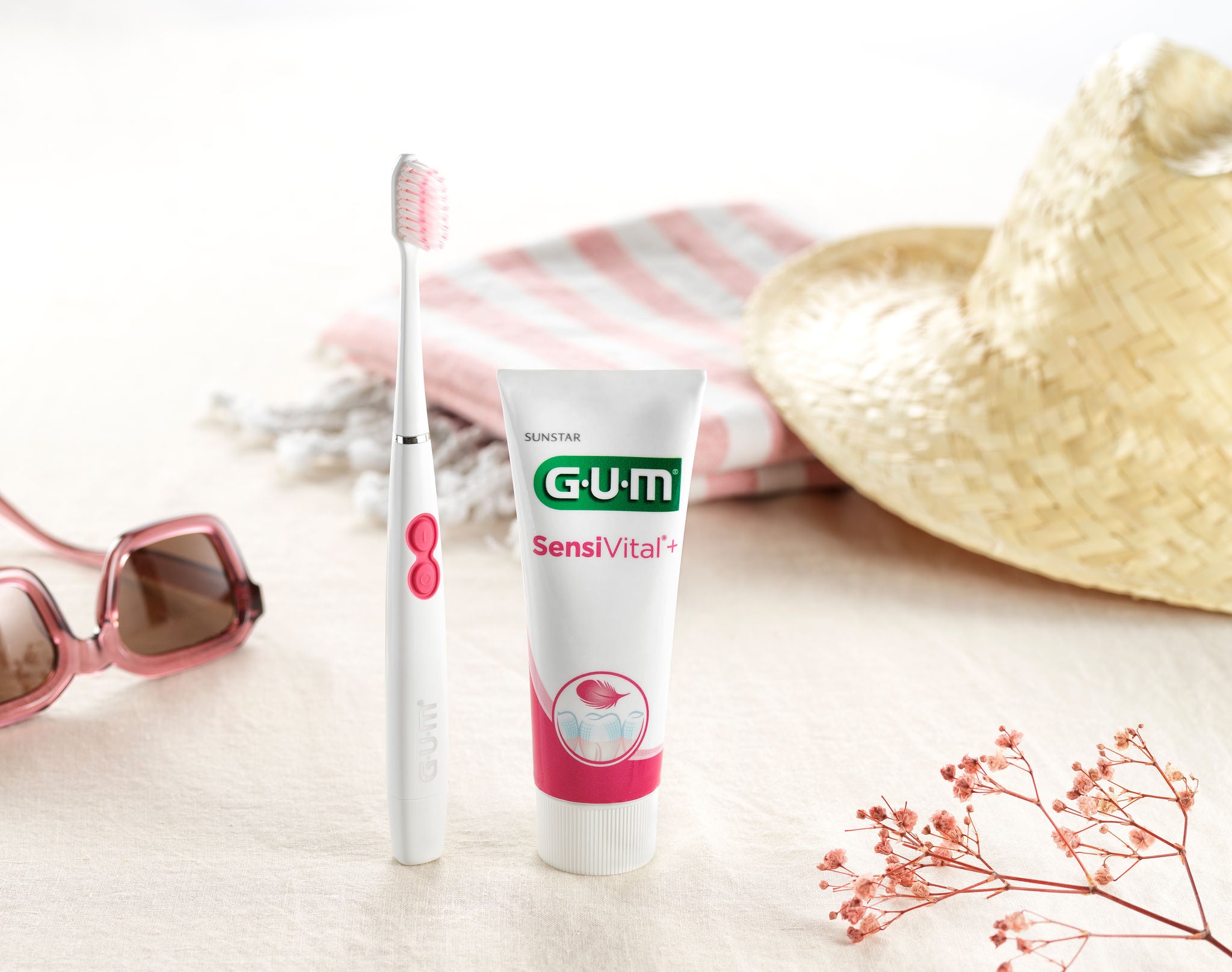 GUM SONIC SENSITIVE Battery Toothbrush and GUM SensiVital toohpaste along with some accessories such as flowers, sunglasses and a summer hat