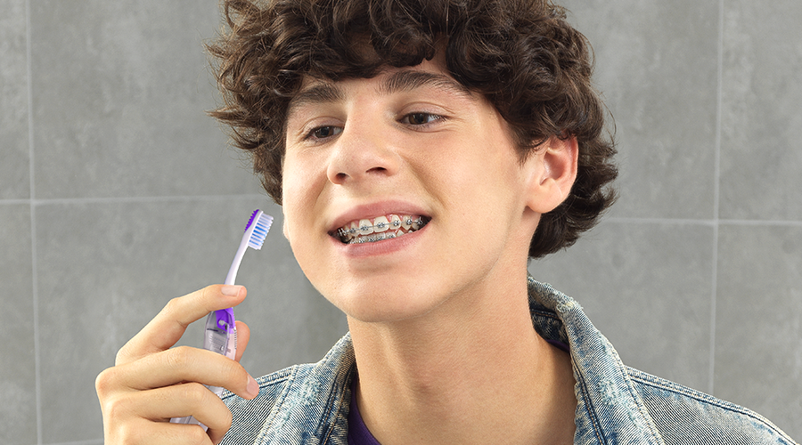 Teenager with braces is starting to brush his teeth with GUM TRAVEL ORTHO Toothbrush