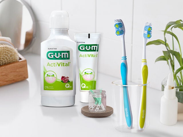 GUM EASY-CLEAN Zahnbürsten in 2 Farben, die in ein Glas gegeben werden, GUM SOFT-PICKS PRO Interdentalbürsten, GUM ActiVital Zahnpasta und GUM ActiVital Mundwasser, alle Produkte im Badezimmer