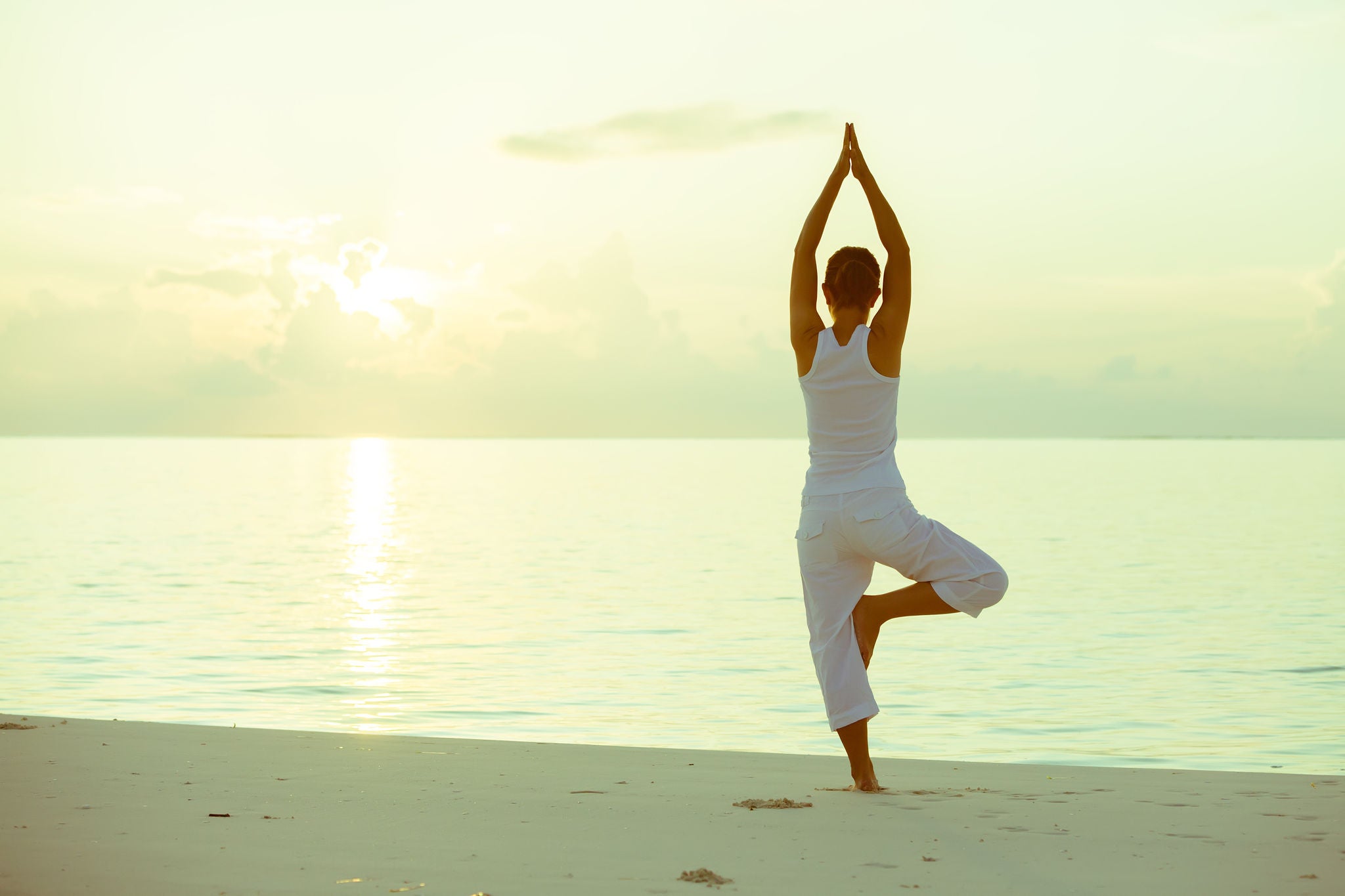 Caucasian woman practicing yoga at seashore