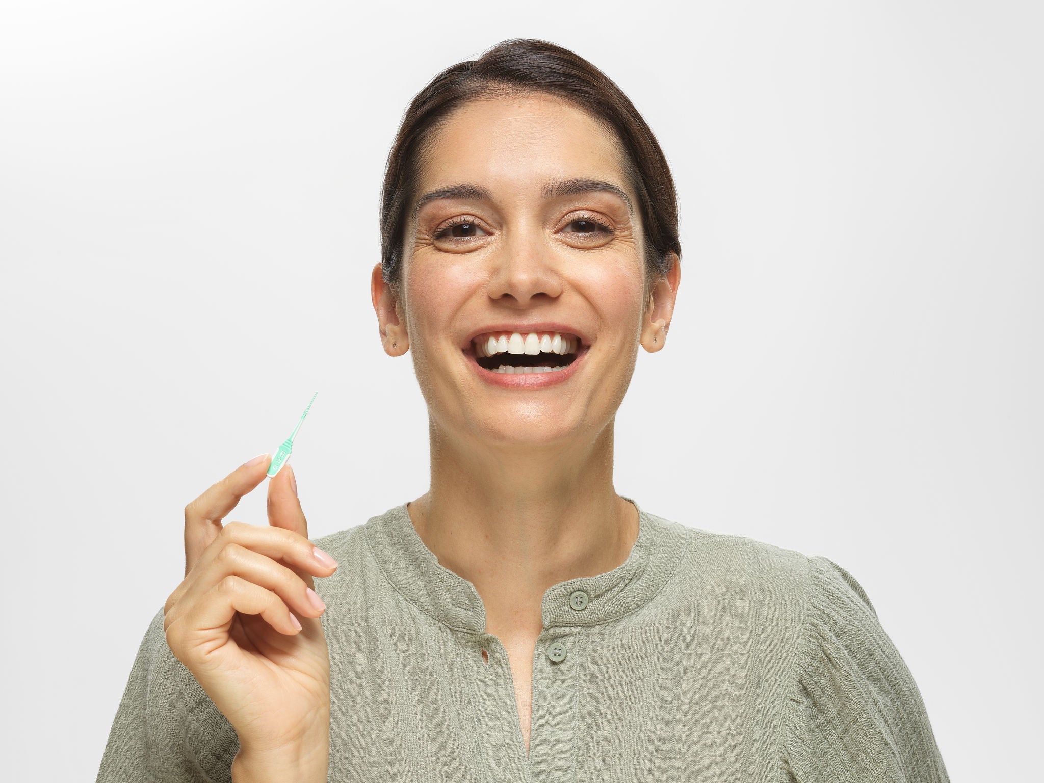 Smiling Woman Holding the GUM SOFT-PICKS MINTY inderdental pick