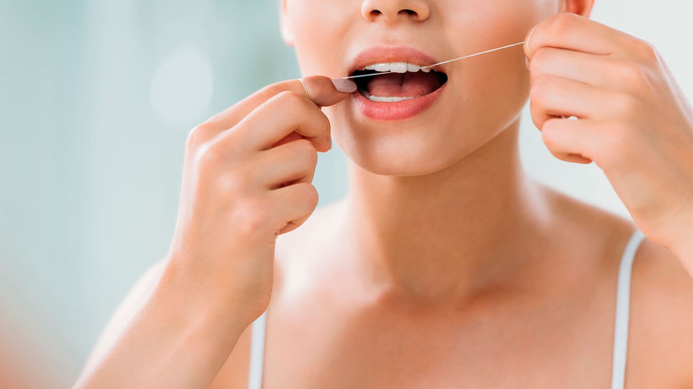 Woman flossing in bathroom Shutterstock_1162480864