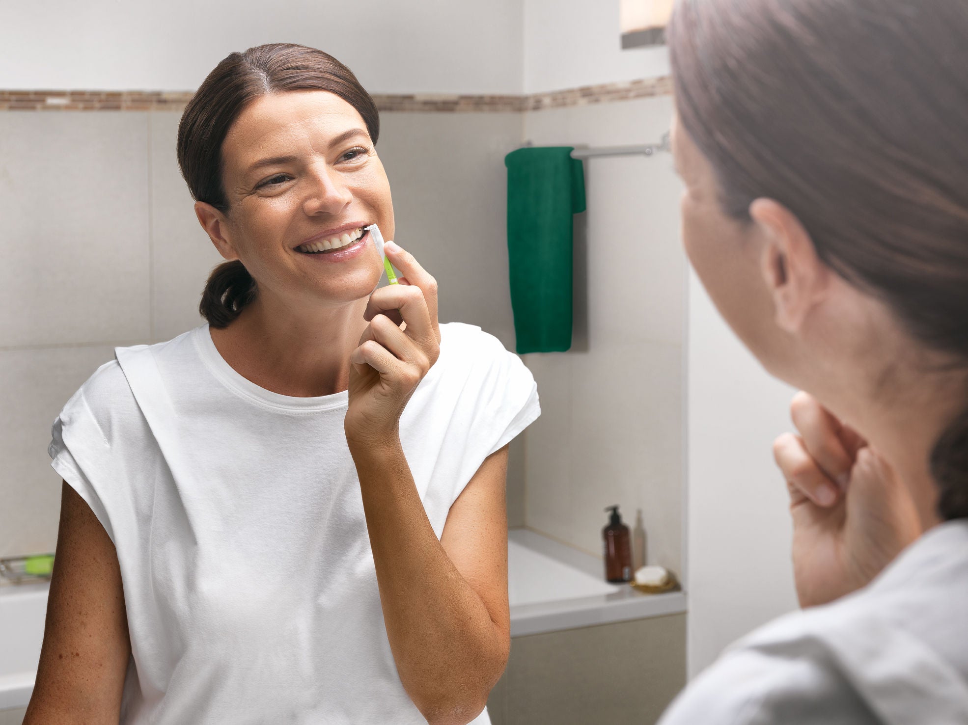 Smiling woman is cleaning between teeth with GUM BI-DIRECTION interdental brush