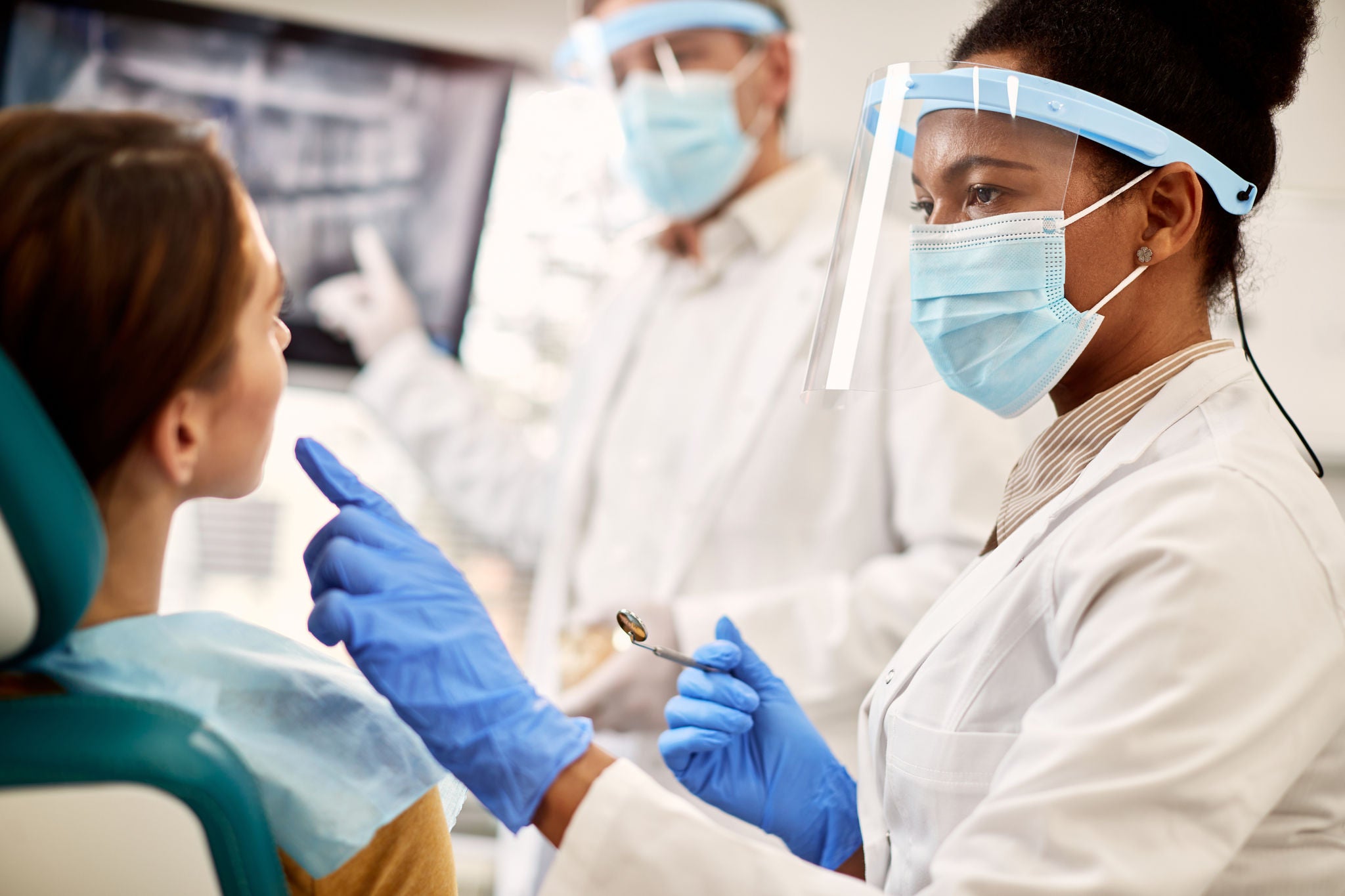 Female-dentist-examining-patient-teeth-during-appointment-at-dental-clinic