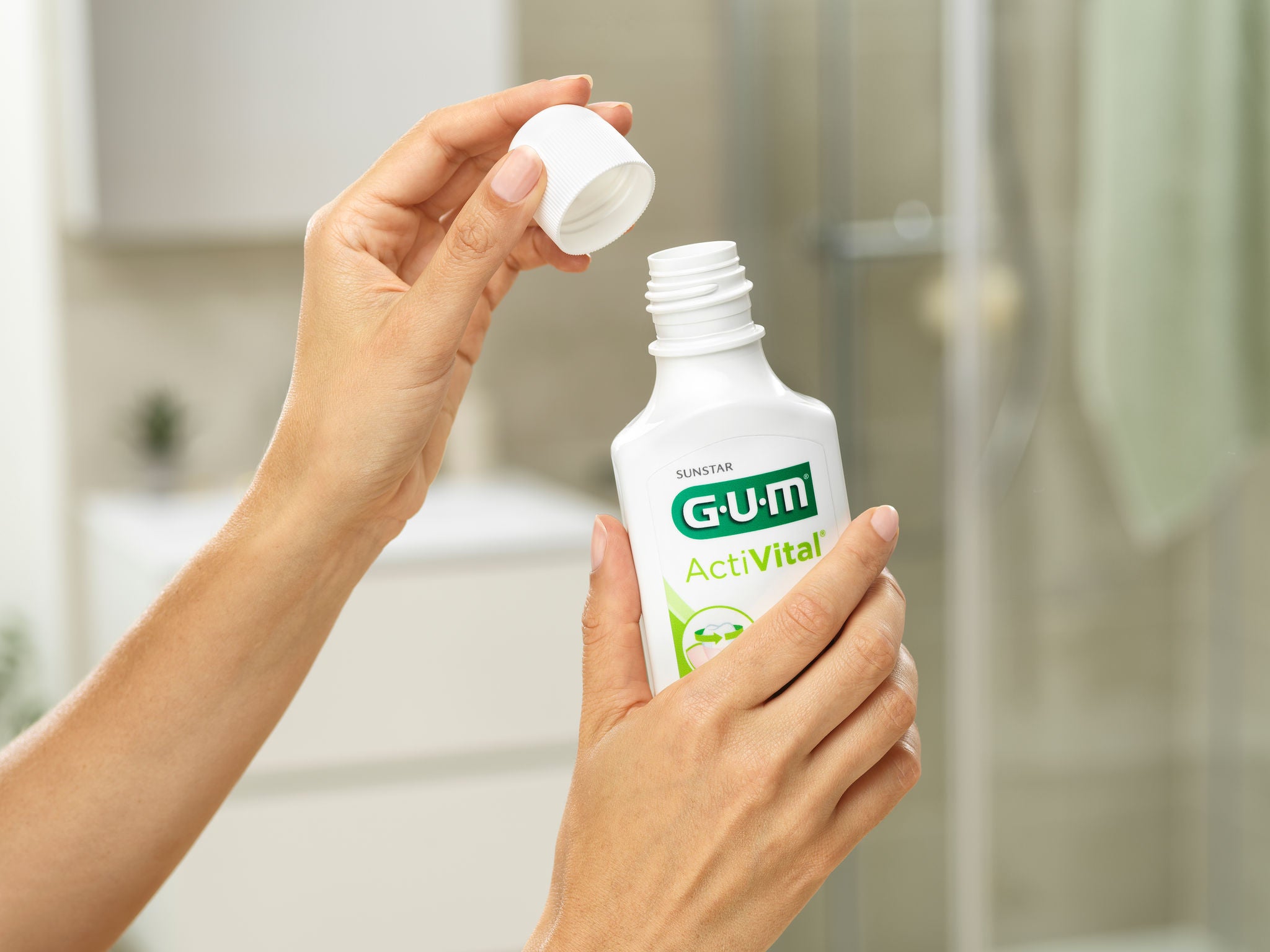 Woman is removing the cap from the bottle of the GUM ActiVital Mouthwash 