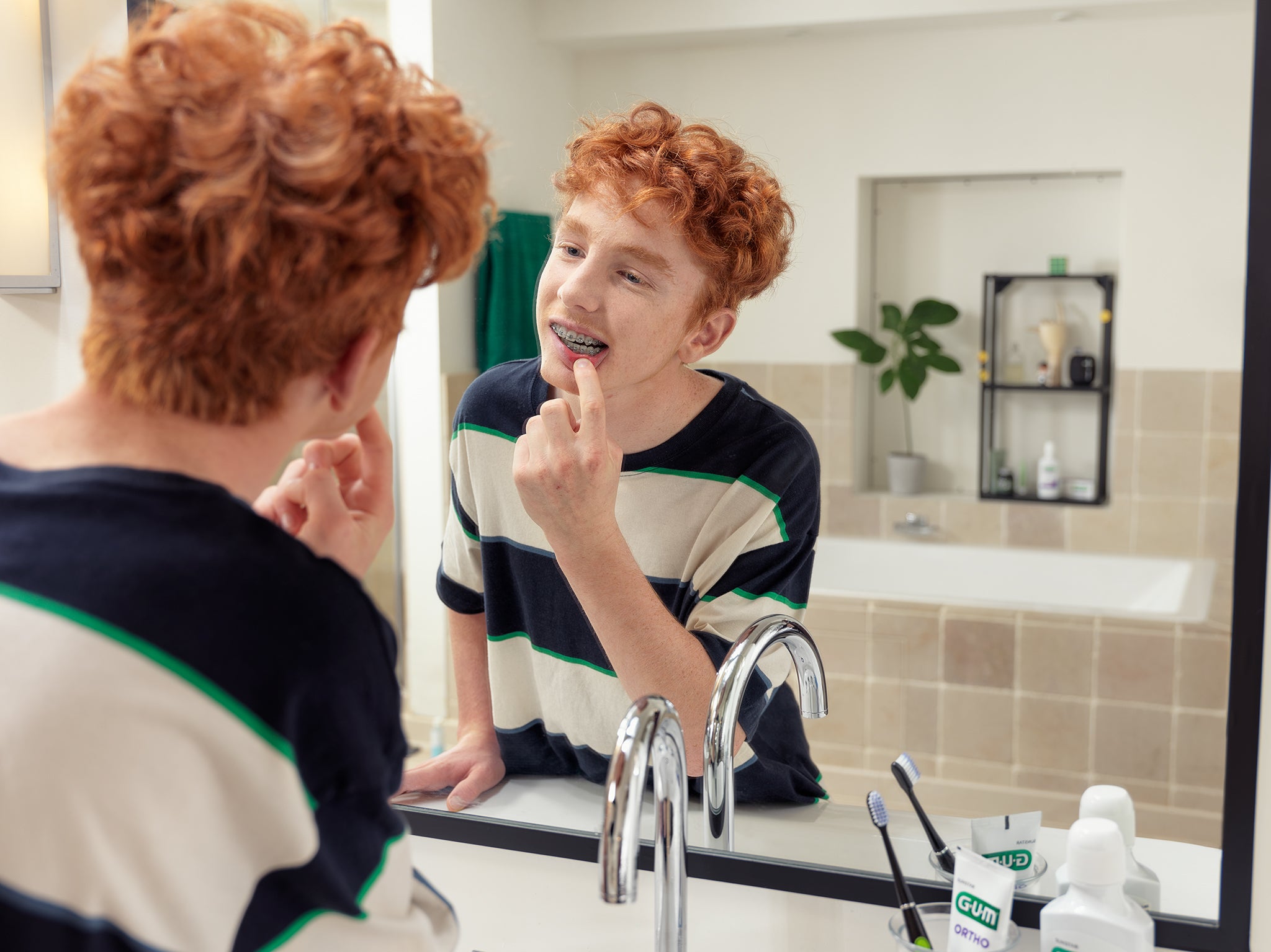 In-context-GUM-SONIC-DAILY-ORTHO-MR-TP-young-boy-checking-braces-in-bathroom, In-context-GUM-SONIC-DAILY-ORTHO-MR-TP-young-boy-checking-braces