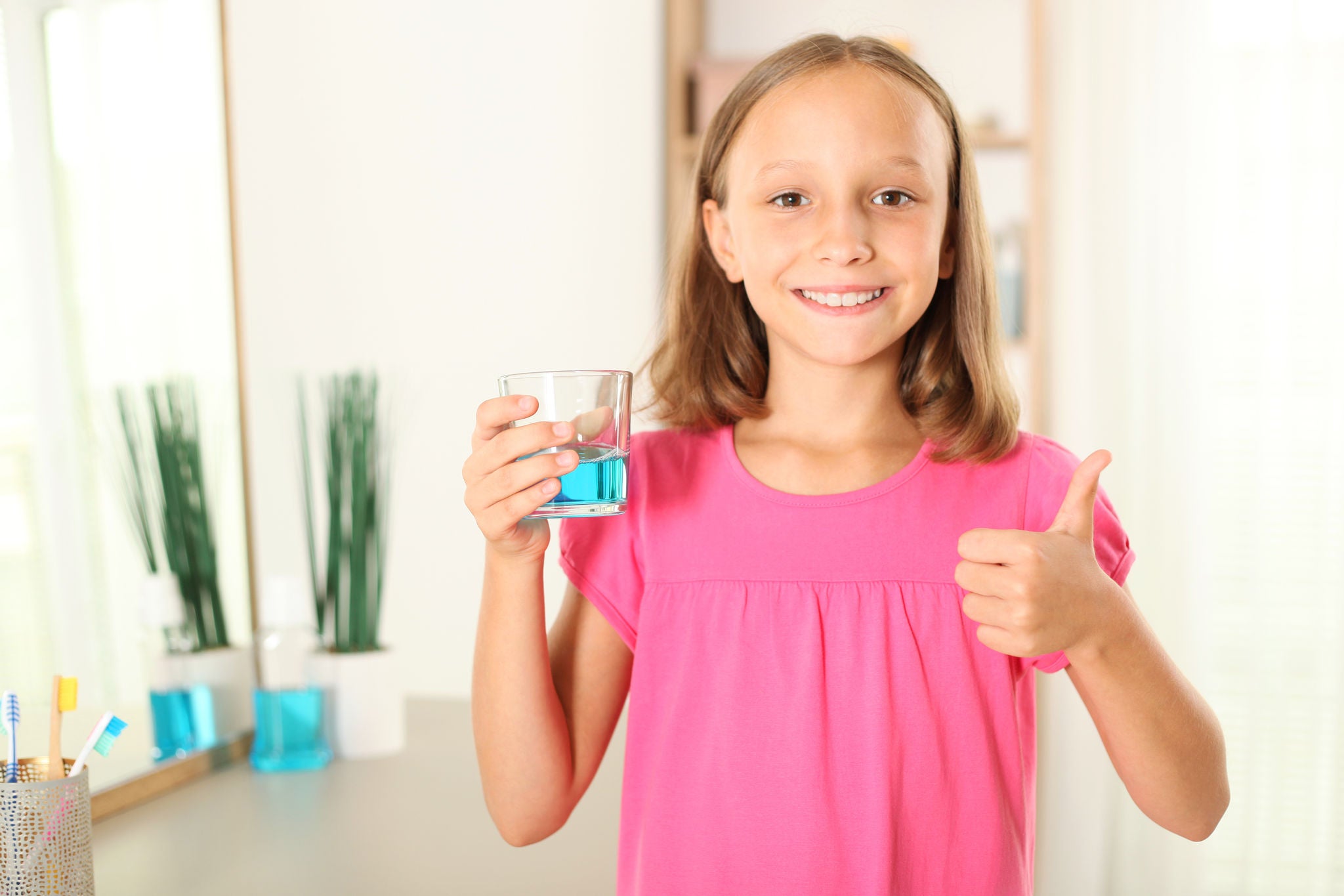 bambina con bicchiere di collutorio in mano