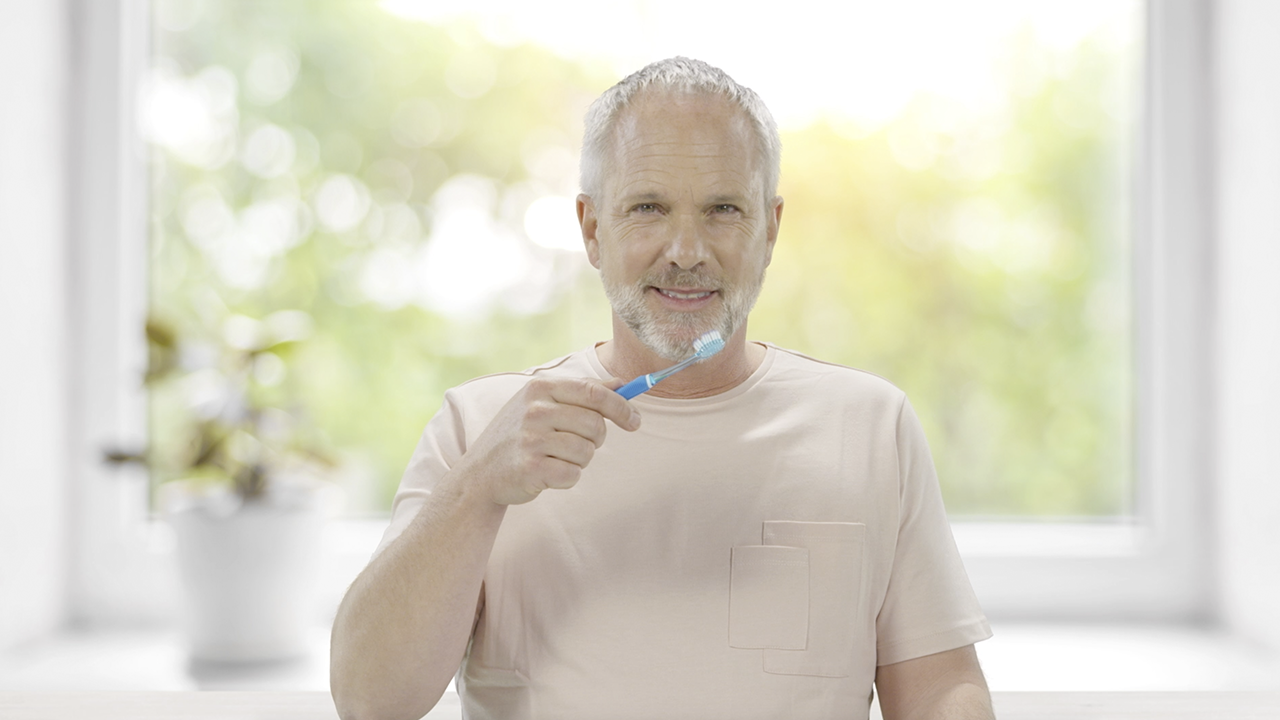 Lächelnder Mann mit Zahnbürste in der Hand
