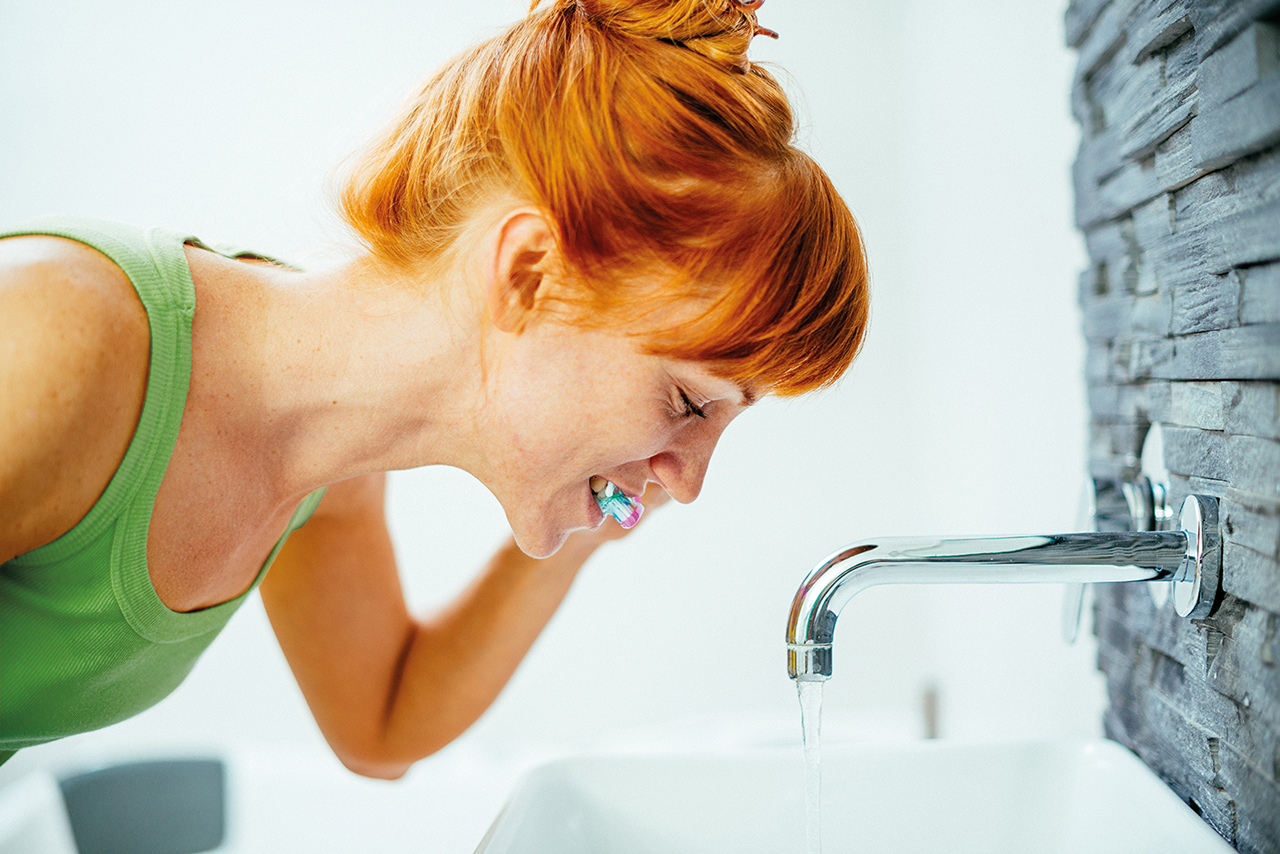 Woman brushing teeth in bathroom with technique toothbrush