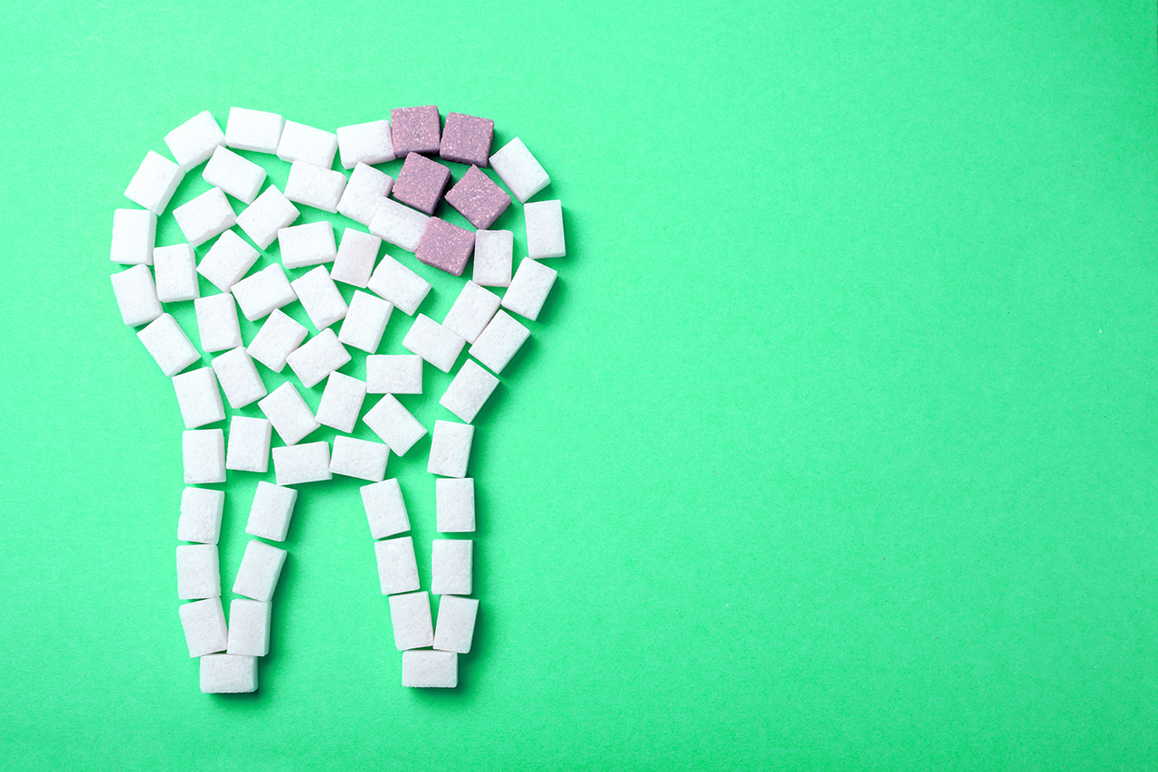 Sugar cubes in shape of tooth green background caries cavities